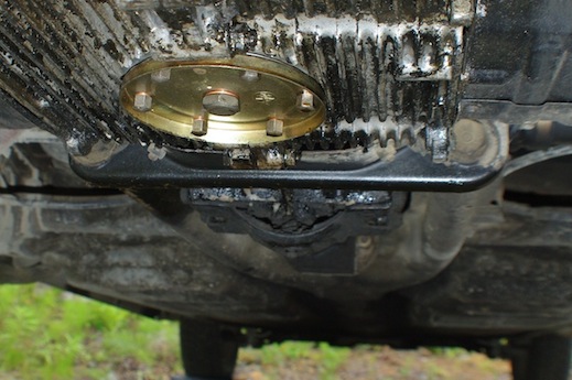 The bracket is on the transmission, just forward of the oil drain plate in this photo.